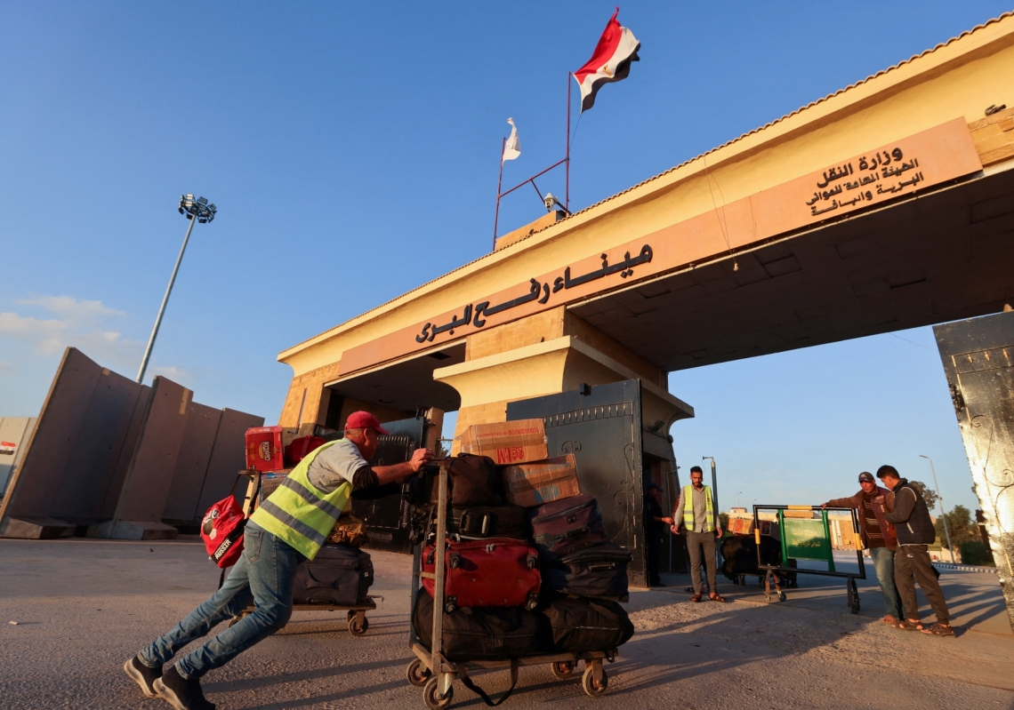A worker pushes a luggage cart with belongings of Palestinians who are trying to get back into Gaza, at the Rafah border crossing during a temporary truce between Hamas and Israel